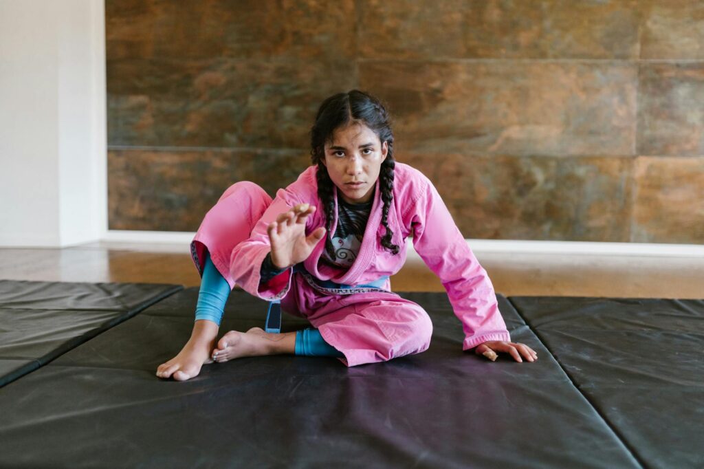 a woman with braided hair wearing a pink gi